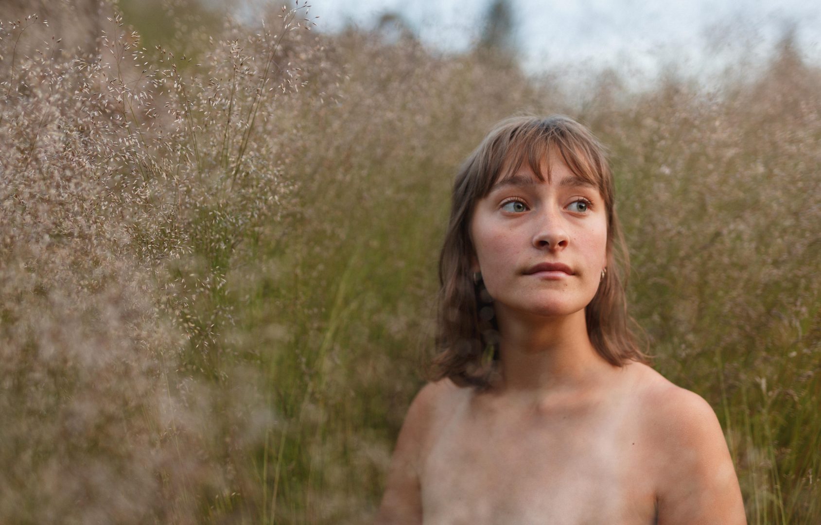 Portrait of a young woman in a field. Evening light with a shallow depth of field.